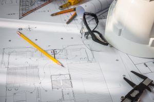 Construction plans with White helmet and drawing tools on blueprints